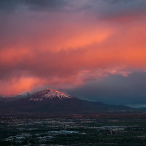 A vertical swash of clouds is lit red by the set sun, other clouds blue, the top of tall mount Nebo catches the glow, too