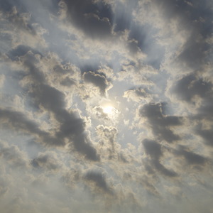 The partly cloudy sky is hazy with smoke casting ray shadows that emminate from the sun in the middle of the photo