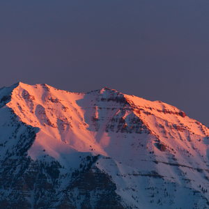 Orange morning light hitting the blue snowy mountain