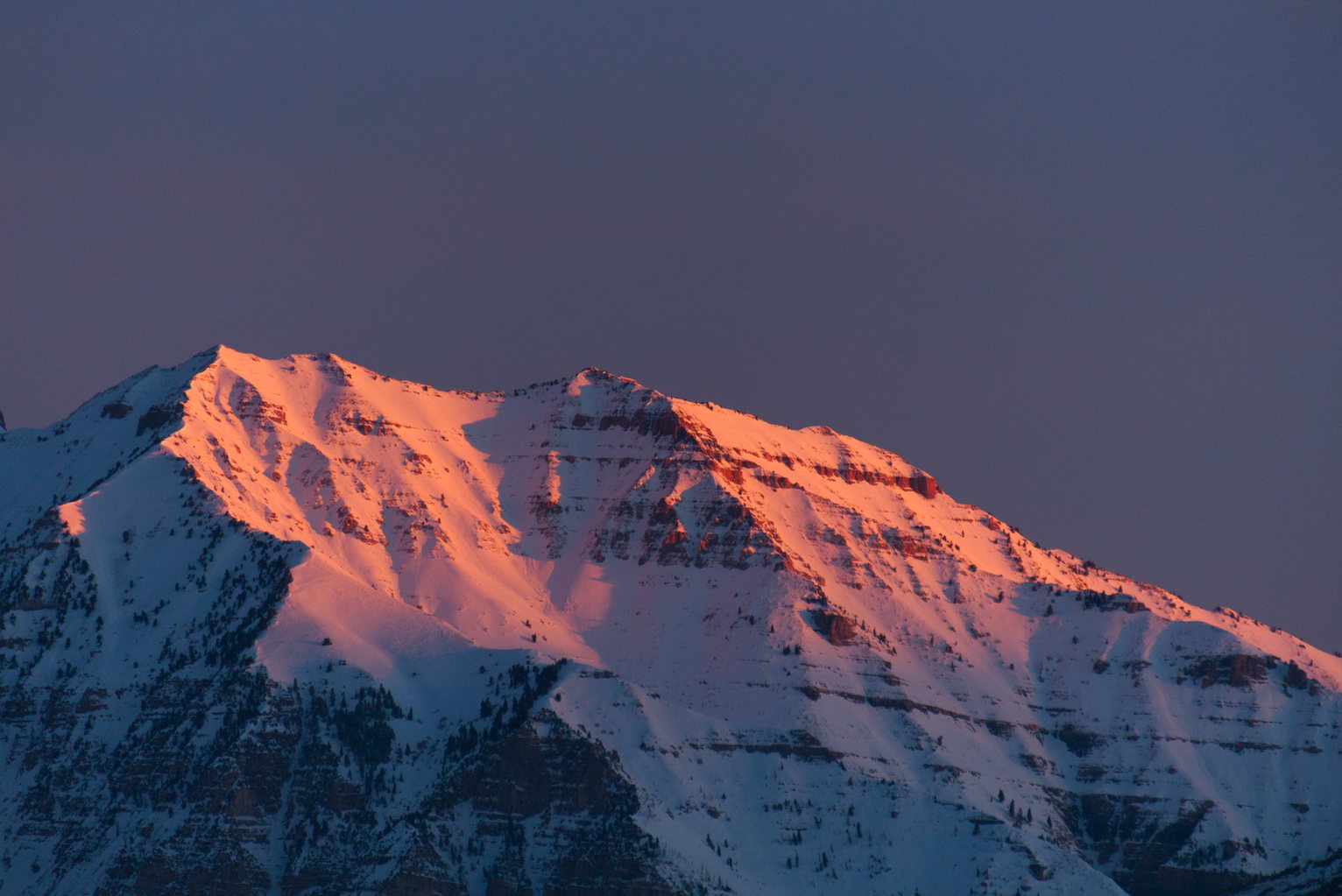 Orange morning light hitting the blue snowy mountain