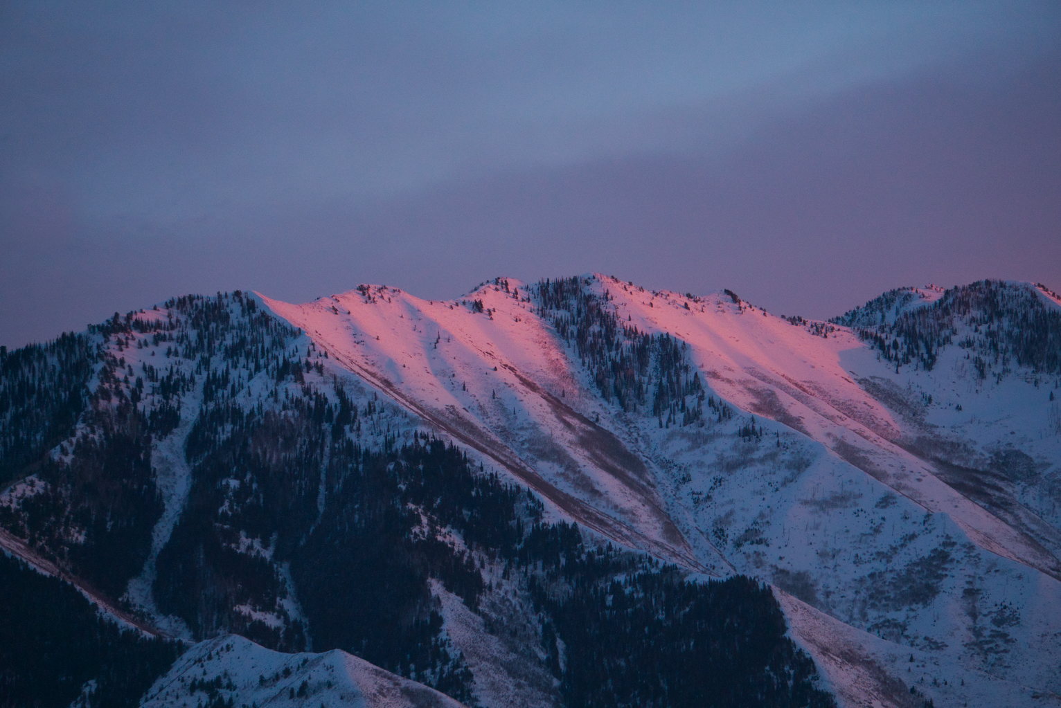 Snowy mountains catch the last pinky flow of sunset
