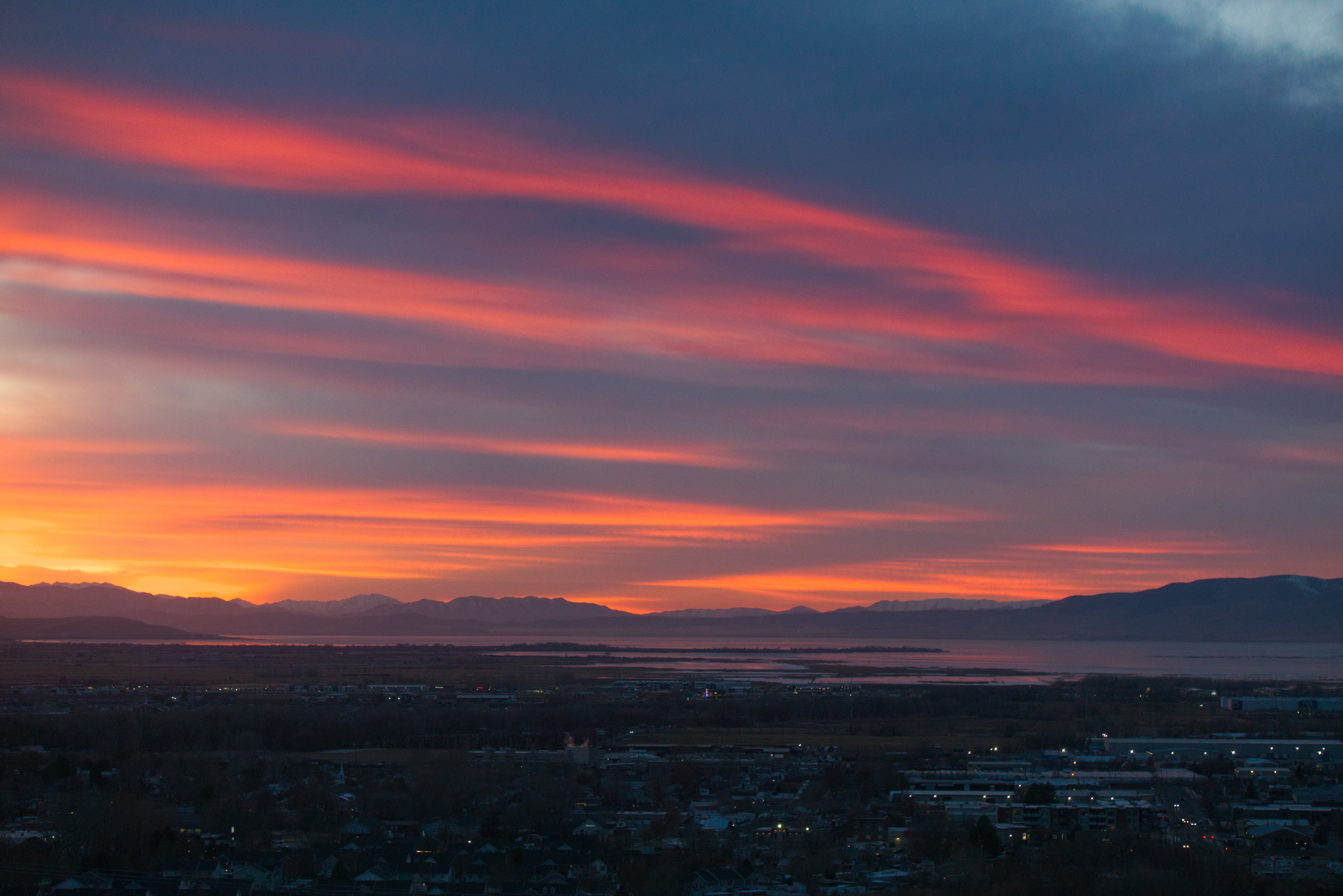 Above a town at sunset the clouds glow in waves