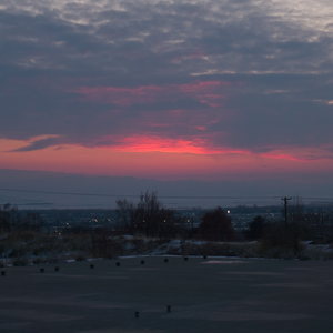 Gray clouds glow red after sunset over town over a concrete slab