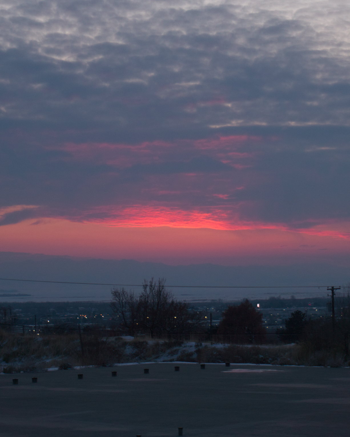 Gray clouds glow red after sunset over town over a concrete slab