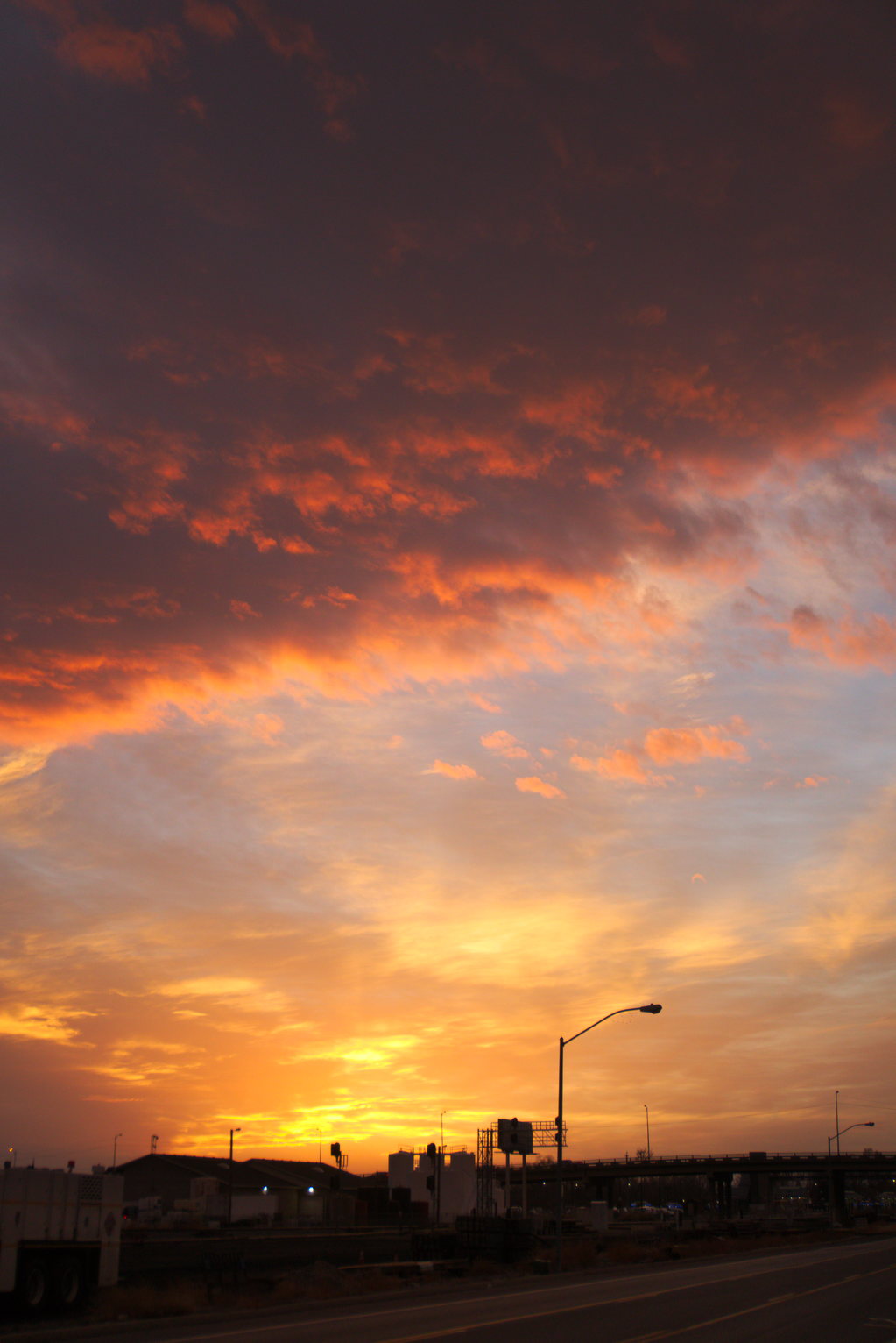Spectacularly lit clouds over buildings and street lights.