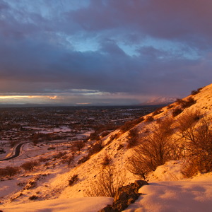 Looking down from a snowy mountainside at a town bathed in strong sunset light