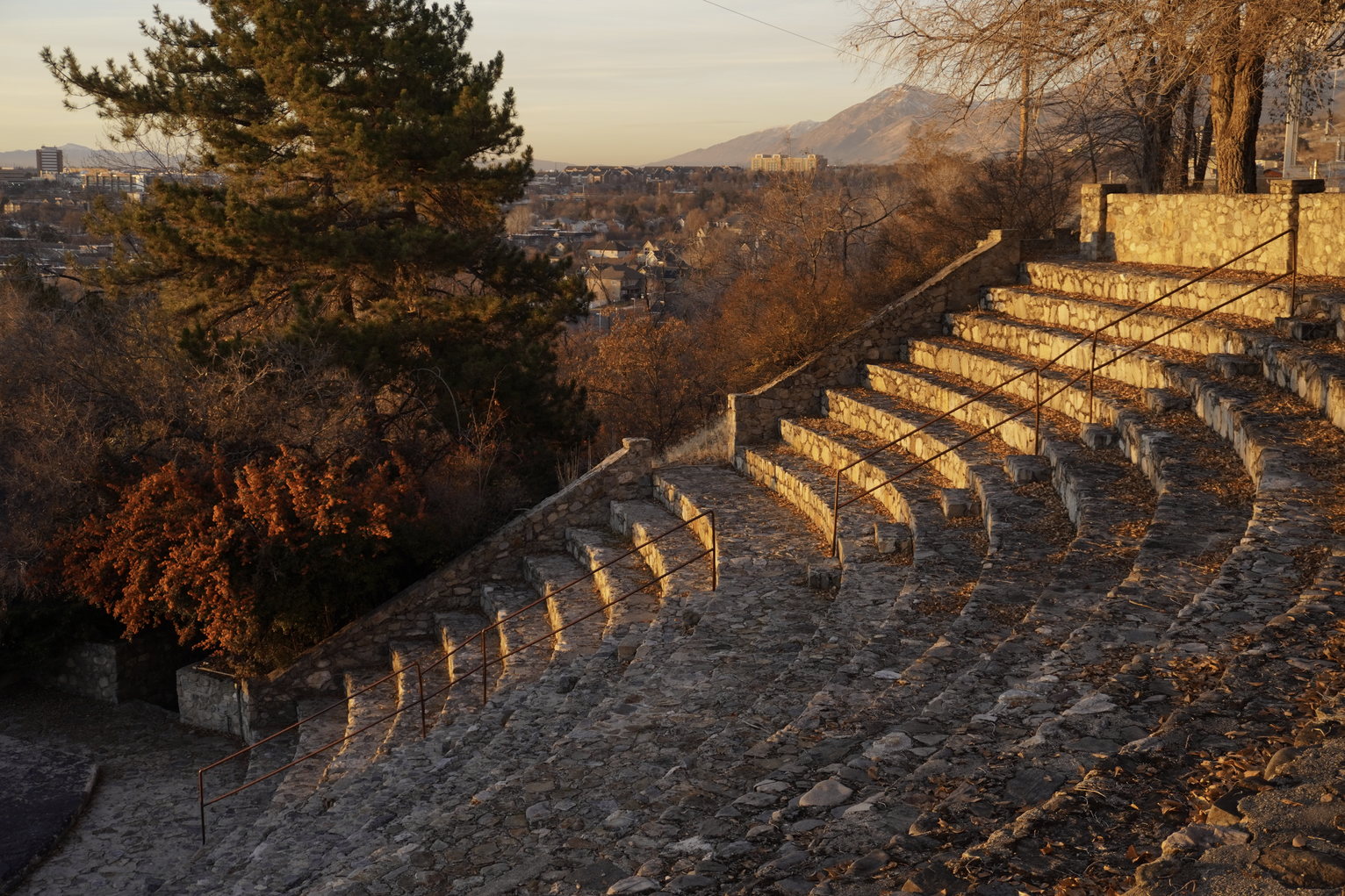 The steps of a small outdoor stone amphitheater lit in golden setting sun light