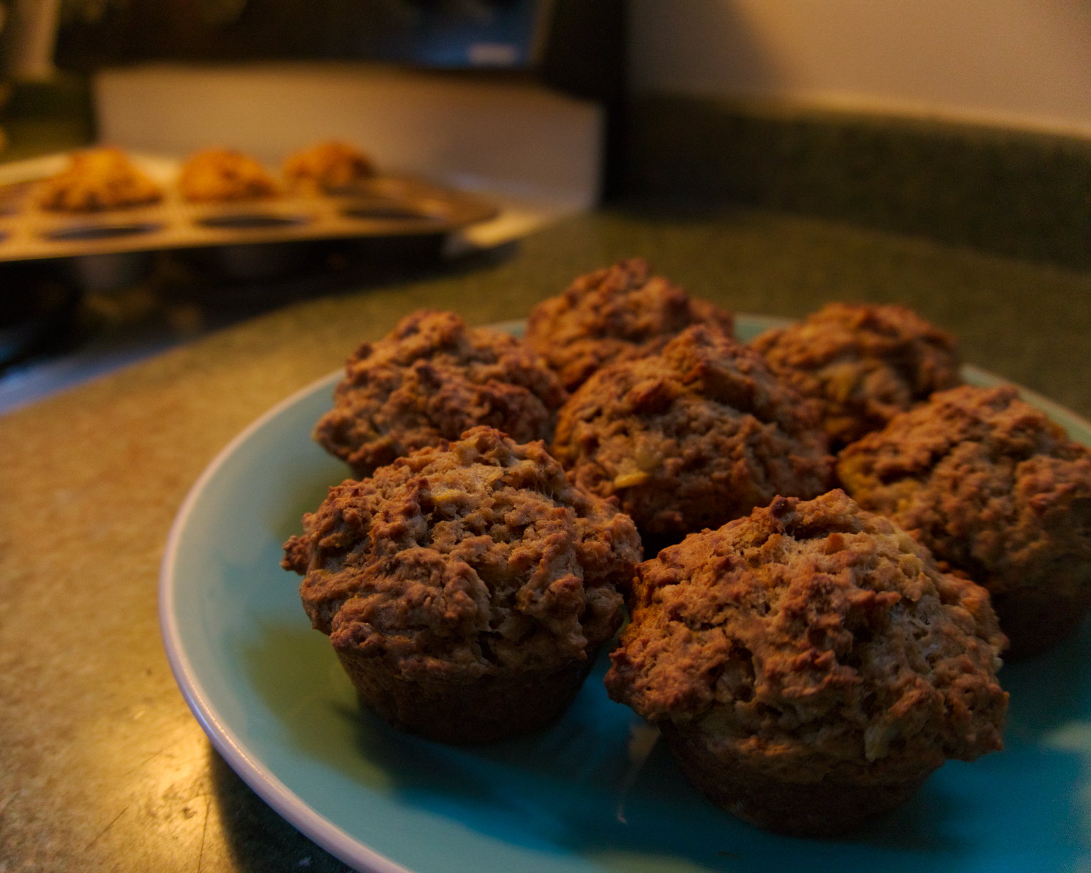 Muffins on a turquoise plate, stove and muffin tin visible in background