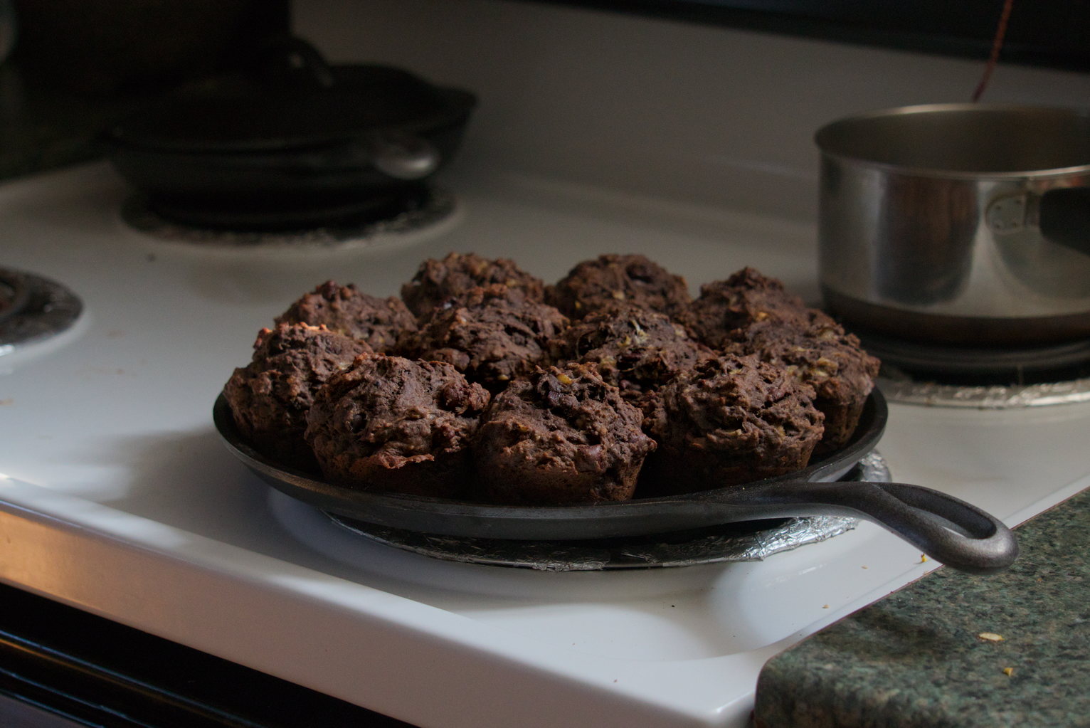 Chocolate banana muffins sitting on a circle griddle pan on a stovetop