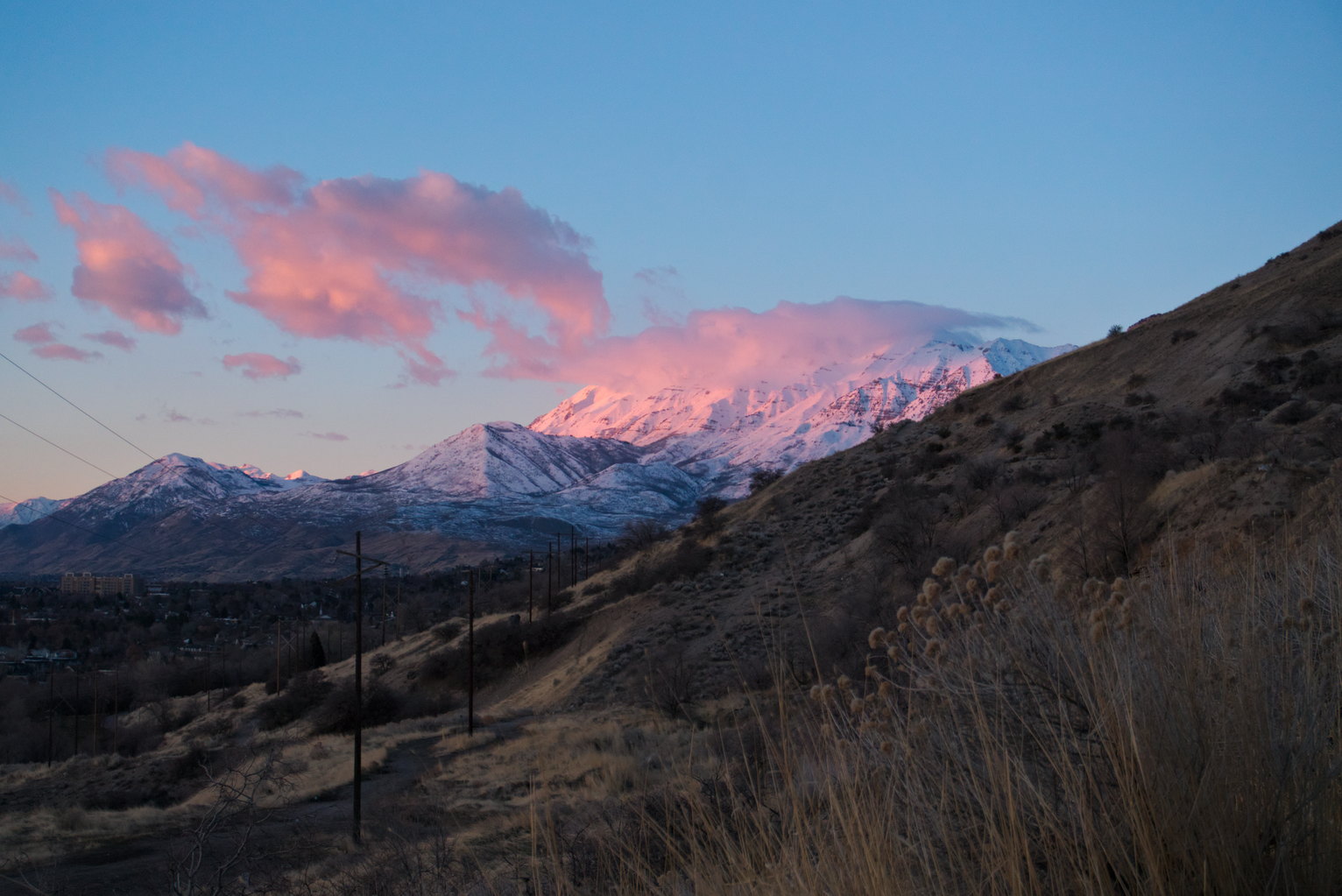 Mount Timpanogos and the clouds streaming off it glow pink