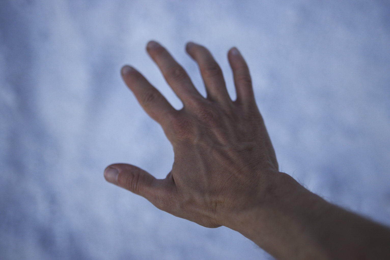 A hand face down in front of a blurry white/blue background.