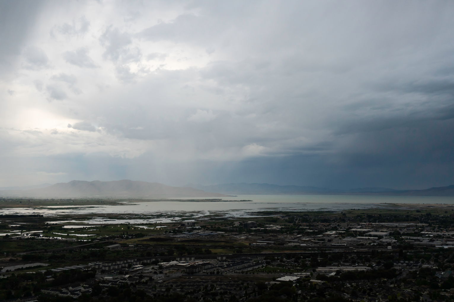 Rain falling over Utah Lake in shadow on the right and in light on the left