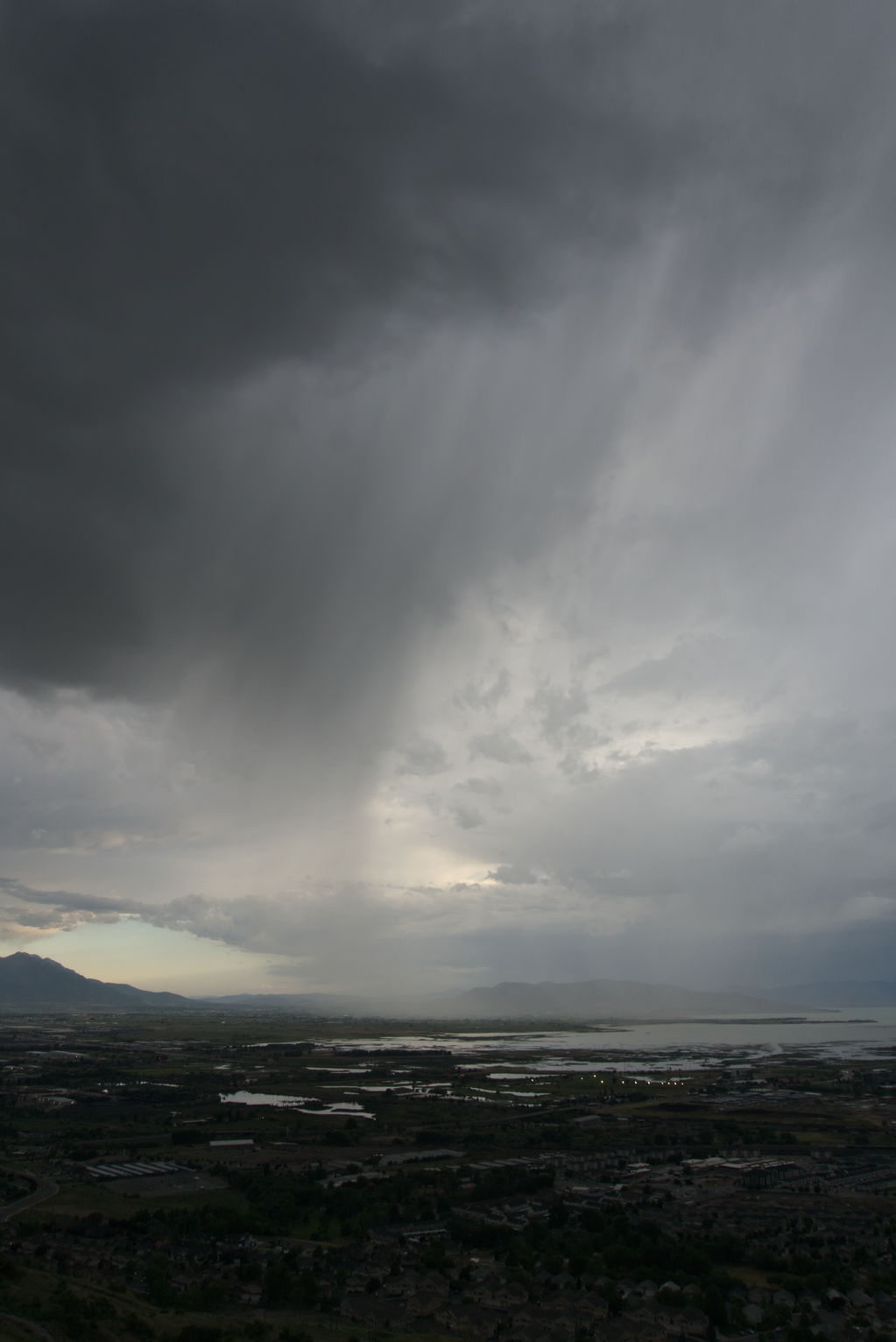 A sheet of rain falling over Utah Lake and town