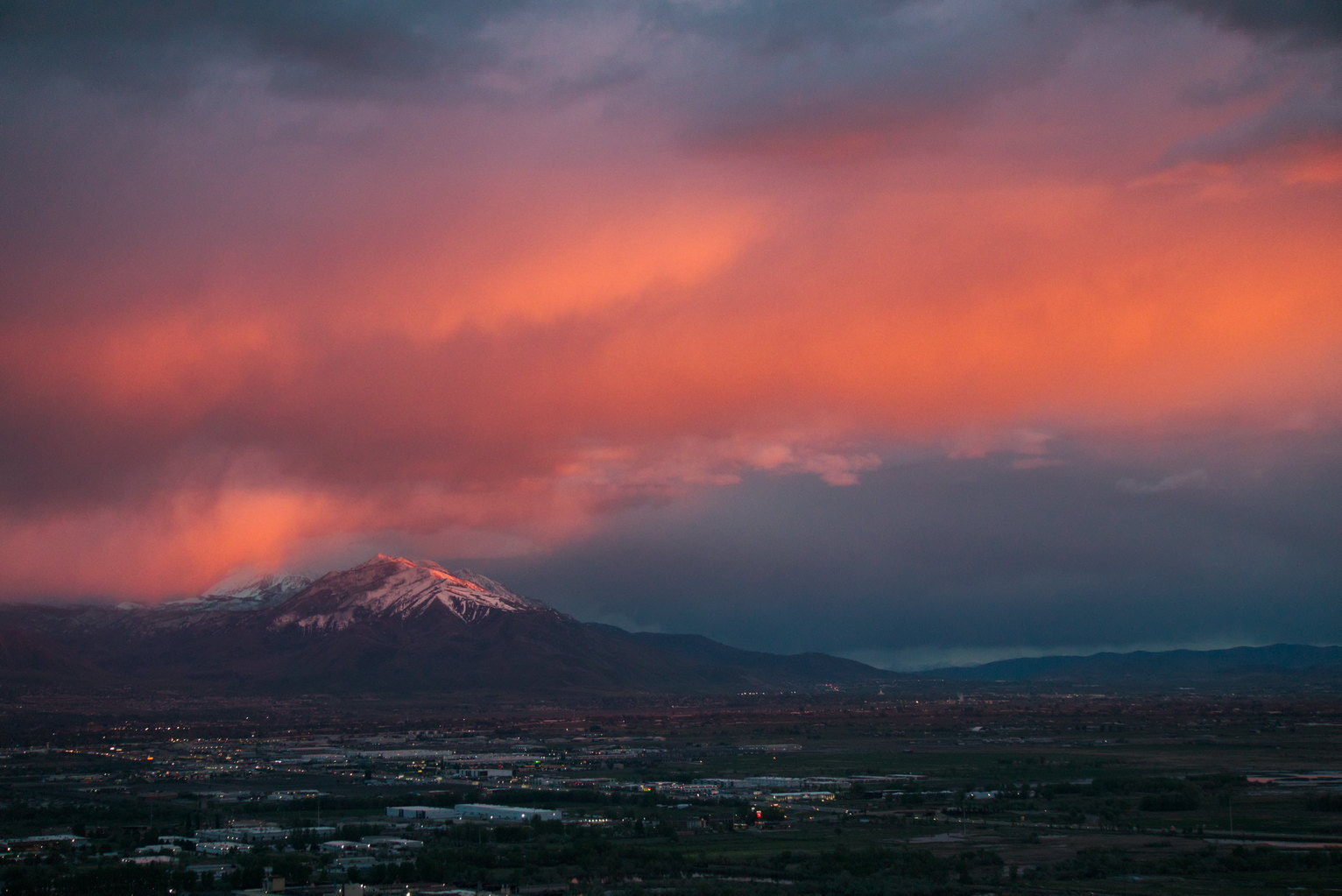 A vertical swash of clouds is lit red by the set sun, other clouds blue, the top of tall mount Nebo catches the glow, too