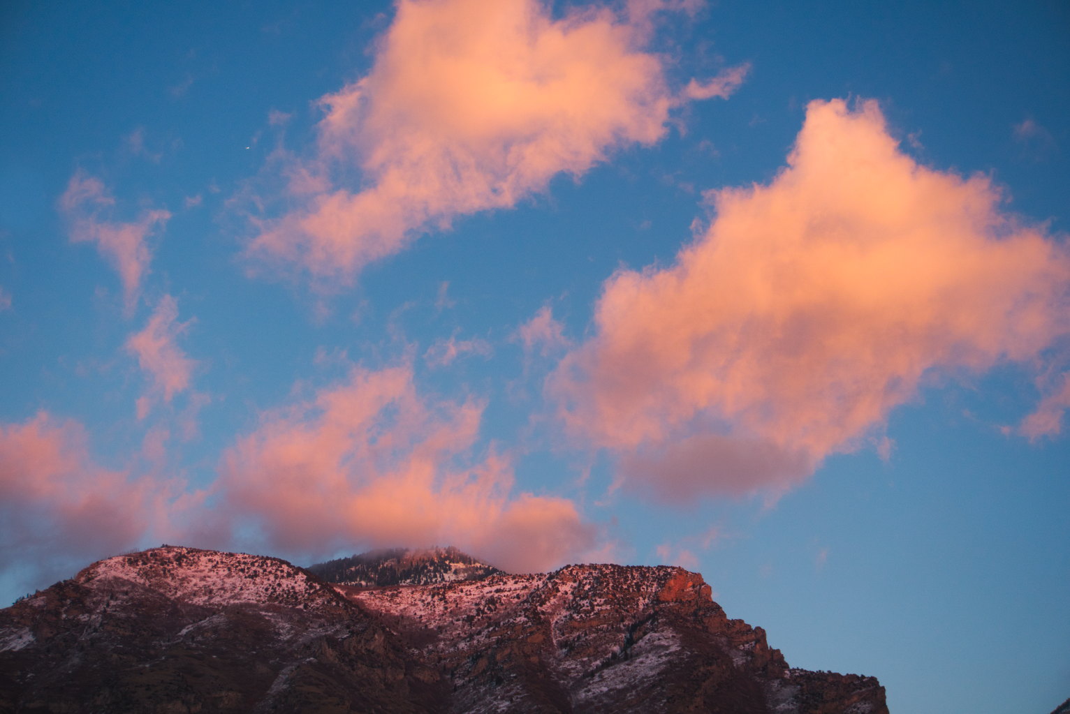 Sunset lit clouds drift of a mountain top