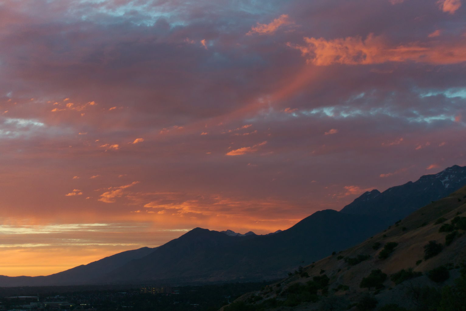 At sunset a swoopy cloud lights up and seems to follow the mountain slope below