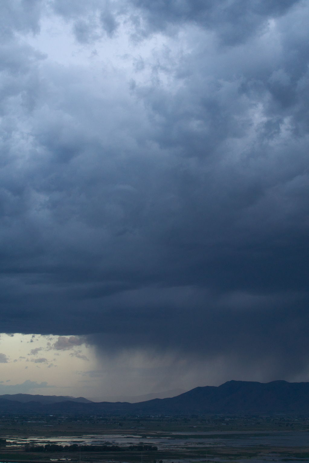 Rain falling out over the mountains, up higher the clouds are light