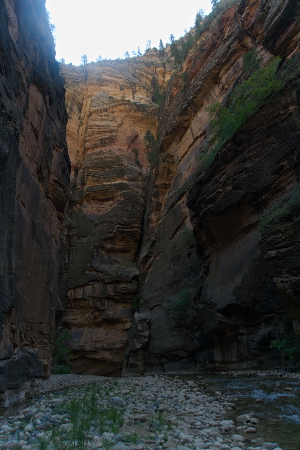 Great tall walls of rock orange and the top, the river and river rocks below